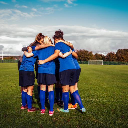 Group of girls in a huddle on a football field